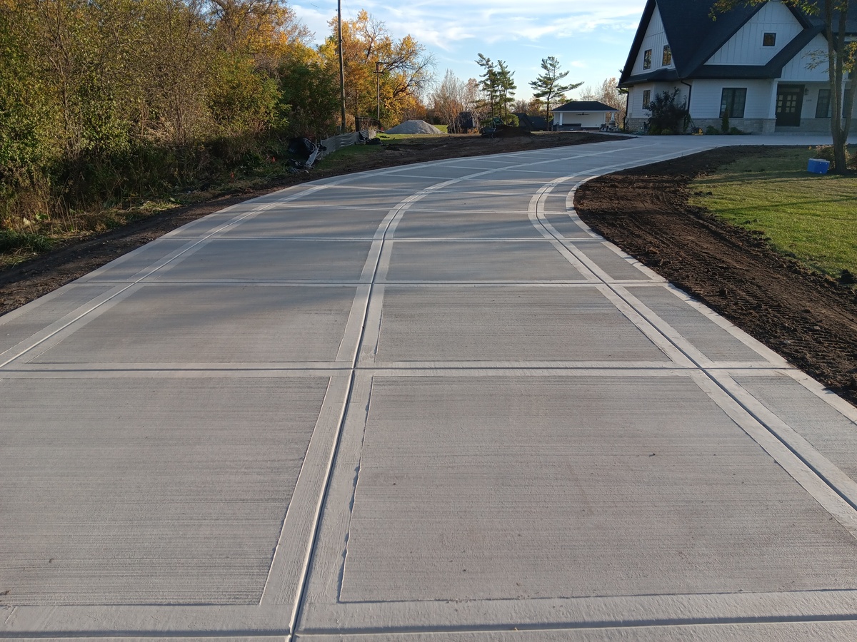 Finished residential concrete driveway curving up to a home